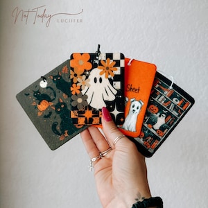 May include: A collection of Halloween-themed air fresheners. Designs include black cats, pumpkins, ghosts, and a dog. One air freshener has the word "Sheet" printed on it. The top left corner of the image has the words "Not Today" and "Lucifer".