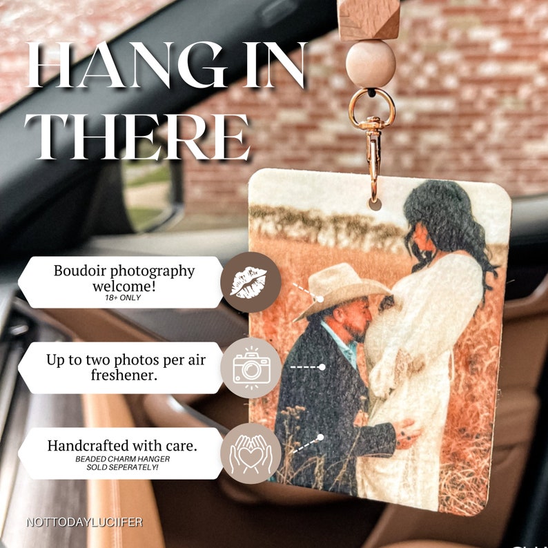 May include: A rectangular car air freshener with a photo of a pregnant person and a person kissing their belly. The air freshener is hanging from a wooden bead and gold-colored clip. Text on the image says "HANG IN THERE".