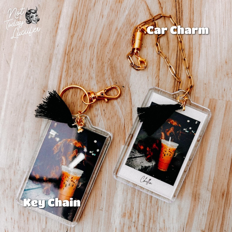 May include: Two clear acrylic charms, one a keyring and the other a car charm, each with a gold-tone chain and clasp. The charms feature a photo of a dog and an iced coffee. The keyring has a black tassel and the car charm has the word "Chillin" written on it.