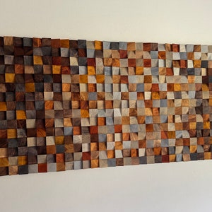 K&ouml;nnte beinhalten: Ein Wandkunstwerk aus Holz mit einem Mosaikmuster. Das Holz ist in verschiedenen Braunt&ouml;nen, Grau- und Blaut&ouml;nen gehalten. Das St&uuml;ck ist rechteckig und hat eine leicht gekr&uuml;mmte Form.
