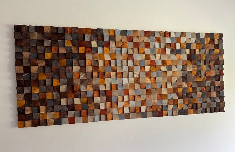 K&ouml;nnte beinhalten: Ein Wandkunstwerk aus Holz mit einem Mosaikmuster. Das Holz ist in verschiedenen Braunt&ouml;nen, Grau- und Blaut&ouml;nen gehalten. Das St&uuml;ck ist rechteckig und hat eine leicht gekr&uuml;mmte Form.