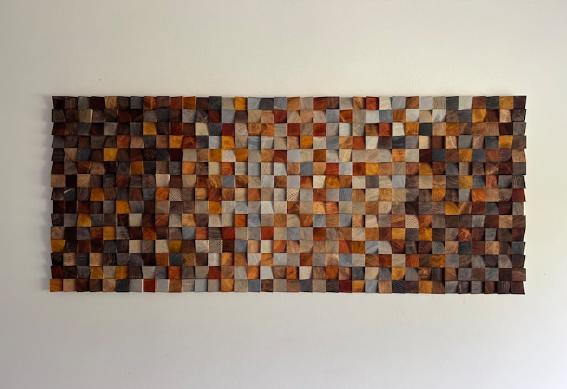 K&ouml;nnte beinhalten: Ein Wandkunstwerk aus kleinen, quadratischen Holzbl&ouml;cken in verschiedenen Braunt&ouml;nen, Graut&ouml;nen und Beige. Die Bl&ouml;cke sind in einem geometrischen Muster angeordnet und schaffen ein strukturiertes und visuell interessantes Design.