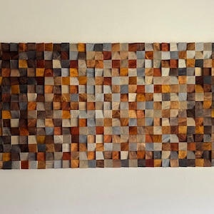 K&ouml;nnte beinhalten: Ein Wandkunstwerk aus Holz mit einem Mosaikmuster. Das Holz ist in verschiedenen Farben, darunter Braun, Grau und Rot. Das St&uuml;ck besteht aus kleinen Holzquadraten, die in einem geometrischen Muster angeordnet sind.