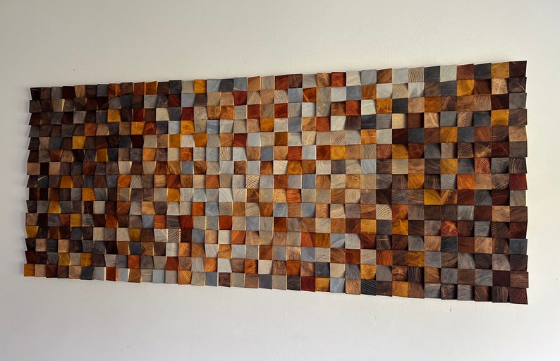 K&ouml;nnte beinhalten: Ein Wandkunstwerk aus Holzbl&ouml;cken in verschiedenen Braunt&ouml;nen, Graut&ouml;nen und Beiget&ouml;nen. Die Bl&ouml;cke sind in Wellenform angeordnet und schaffen ein einzigartiges und modernes Design.