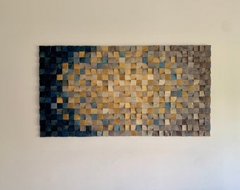 Könnte beinhalten: Ein Wandkunstwerk aus Holzblöcken in Blautönen, Braun- und Beigetönen. Die Blöcke sind in einem geometrischen Muster angeordnet, das einen Farbverlauf von Dunkelblau bis Hellbeige erzeugt.