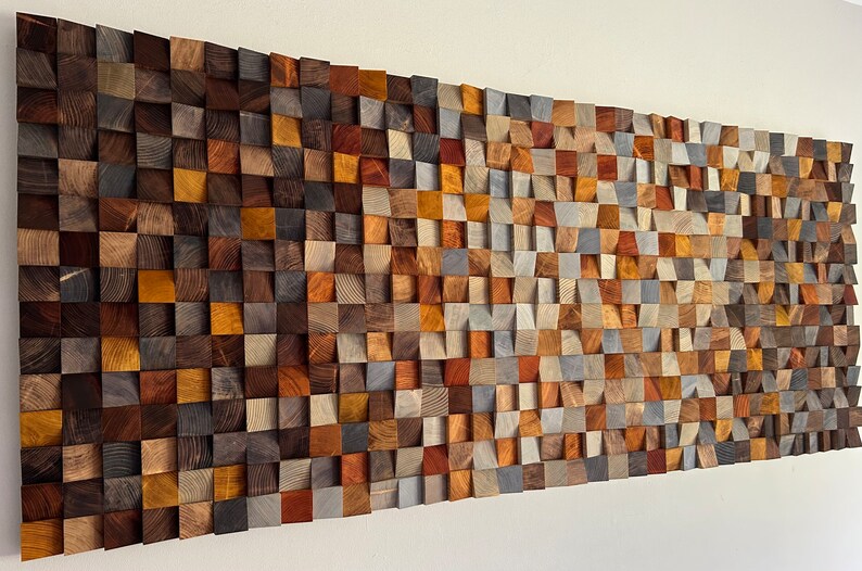 K&ouml;nnte beinhalten: Ein Wandkunstwerk aus Holz mit einem Wellenmuster. Das Holz ist in verschiedenen Farben, darunter Braun, Grau und Orange. Das Holz ist in einem Gittermuster angeordnet.