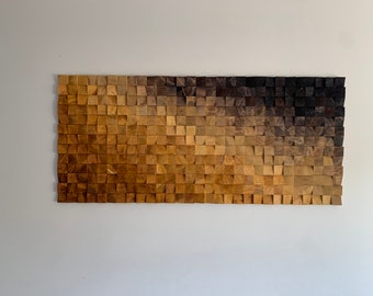 May include: A wall art piece made of wood blocks in shades of brown, transitioning from light to dark. The blocks are arranged in a staggered pattern, creating a textured and abstract design.