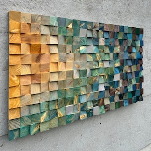 Puede incluir: Una pieza de arte de pared hecha de cuadrados de madera en tonos de amarillo, verde, azul y marrón. Los cuadrados están dispuestos en un patrón escalonado, creando un efecto de degradado.