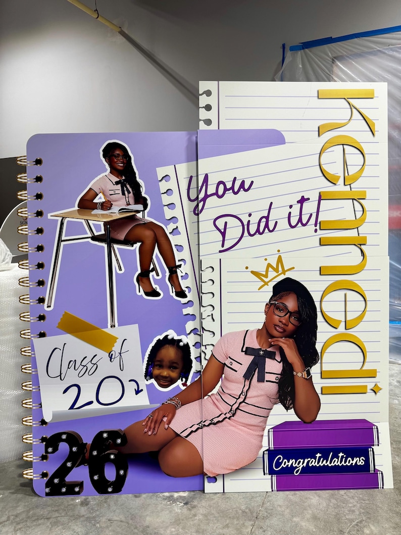 Pu&ograve; includere: Un oggetto di scena a tema laurea con un design a quaderno a spirale. Presenta il testo "Class of 2022", "You Did It!" e "Congratulations", insieme al nome "Kennedy". Il design incorpora immagini di una persona con un vestito rosa.