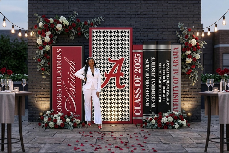 Pu&ograve; includere: Una scena di celebrazione della laurea con una donna in completo bianco che posa davanti a pannelli decorativi. I pannelli presentano il logo dell'Universit&agrave; dell'Alabama, la scritta "Congratulazioni Asiriah" e "Classe del 2025". Composizioni floreali rosse e bianche incorniciano la scena.