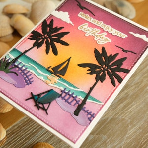 May include: A handmade birthday card depicting a beach scene with palm trees, a sailboat, and a beach chair. The card features a sunset backdrop and the text "Relax and enjoy your birthday".