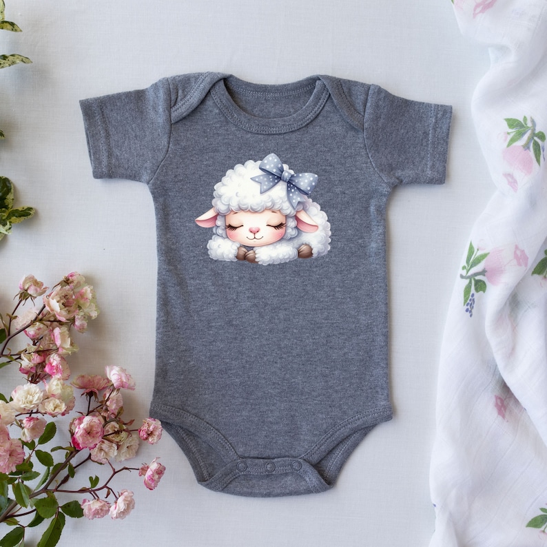 Pu&ograve; includere: Un body a maniche corte grigia con un agnello bianco che indossa un fiocco blu con pois bianchi. L'agnello sta dormendo con gli occhi chiusi.