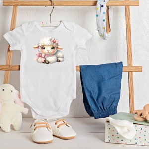 Pu&ograve; includere: Un body bianco per neonato con un adorabile agnello di cartone animato che indossa un fiocco rosa. L'agnello &egrave; seduto su uno sfondo bianco.