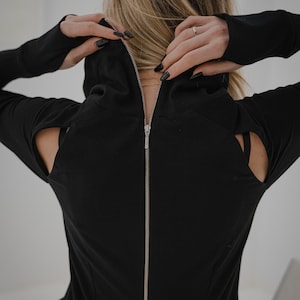 Peut inclure: Chemise noire &agrave; manches longues avec une fermeture &eacute;clair dans le dos et des &eacute;paules d&eacute;coup&eacute;es.