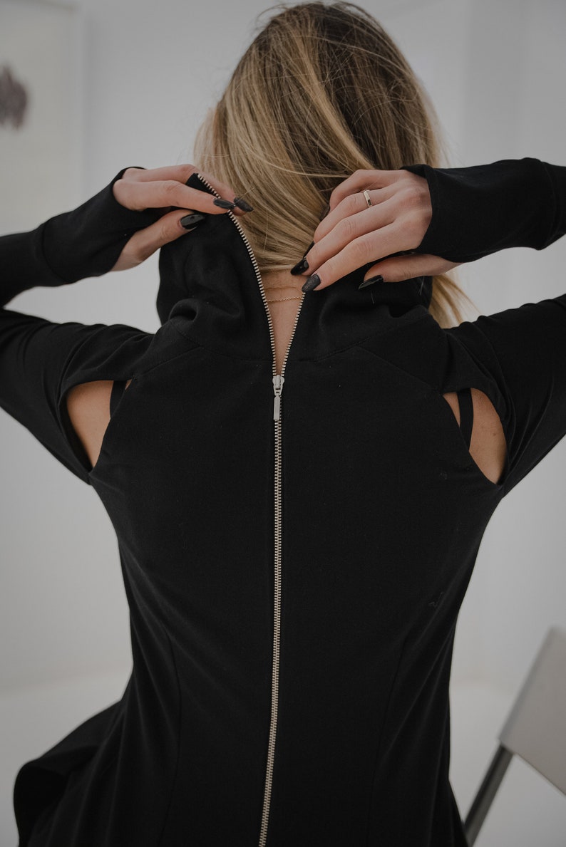 Peut inclure: Chemise noire &agrave; manches longues avec une fermeture &eacute;clair dans le dos et des &eacute;paules d&eacute;coup&eacute;es.