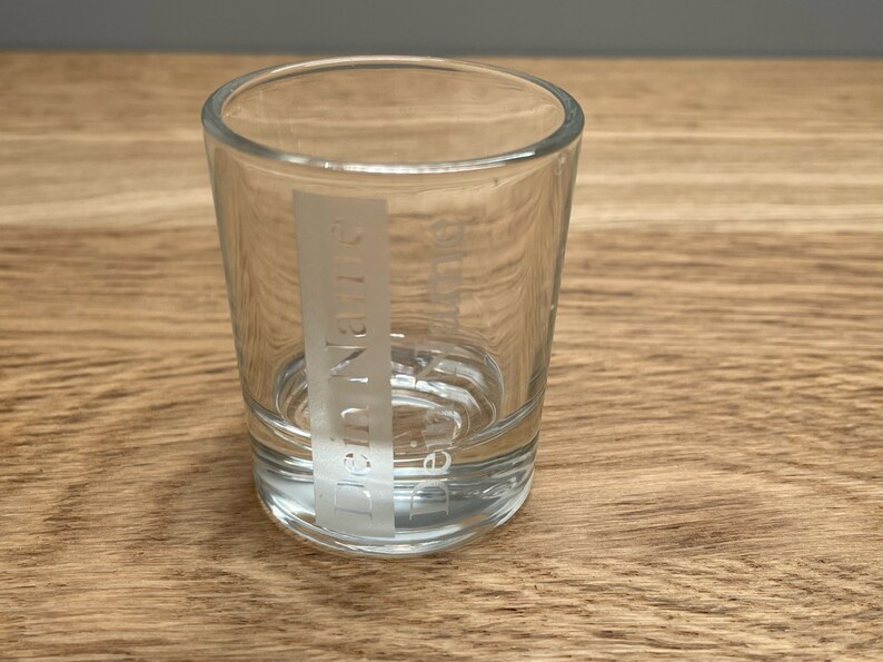 Op de afbeelding: Een helder glazen shotglas met het woord "Drink Name" gegraveerd aan de zijkant.