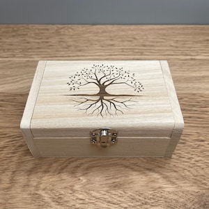 May include: A wooden box with a hinged lid and a metal latch. The box is decorated with a laser-engraved image of a tree with roots.