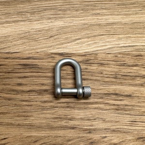 Può includere: Un moschettone rapido in metallo argentato con chiusura a vite.