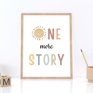 May include: A framed print with a colorful sun and the text "ONE more STORY" in a whimsical font. The print is on a white background and has a light wood frame.