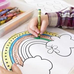 May include: A child is colouring a rainbow with crayons on a white sheet of paper. The rainbow has yellow, blue, brown, and green stripes. The child is using a green crayon to colour the top of the rainbow.