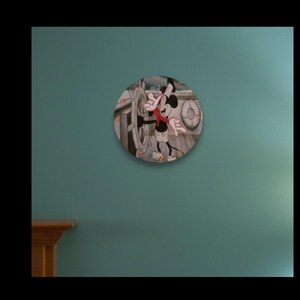May include: Circular wall clock depicting Mickey Mouse in a vintage cartoon style, steering a ship. The clock face is white with black hands, set against a teal wall. The design evokes classic animation and would suit a child's room.