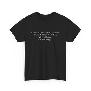 Peut inclure: T-shirt noir avec texte blanc : « I Gotta Test The Mic First. Then I Start Talking While Muted. I'm Not Stupid. » Le t-shirt a des manches courtes et un col rond.