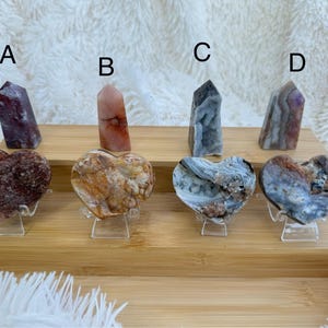 May include: Four heart-shaped agate slices on stands, with four agate towers labelled A, B, C, and D. The heart-shaped slices are in shades of brown, white, and grey. The towers are in shades of pink, red, and grey.