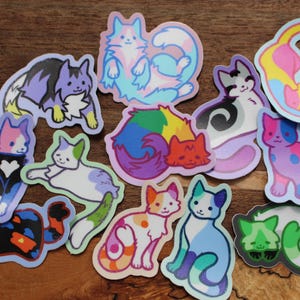 Puede incluir: Un conjunto de 13 pegatinas de gato coloridas con varios diseños y combinaciones de colores. Las pegatinas muestran gatos en diferentes poses, incluyendo acurrucados, sentados y de pie. Las pegatinas son perfectas para agregar un toque de fantasía a las computadoras portátiles, botellas de agua, diarios y otras superficies.