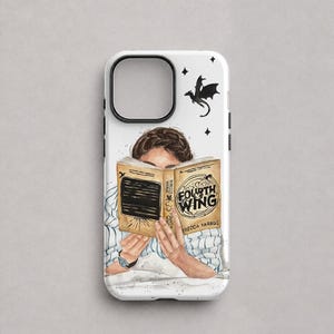 Może przedstawiać: Białe etui na telefon z ilustracją osoby czytającej książkę pod tytułem Fourth Wing autorstwa Rebecci Yarros. Wzór zawiera czarną sylwetkę smoka, małe gwiazdki oraz postać ubraną w koszulę w biało-niebieskie paski.