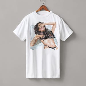 May include: White t-shirt with an illustration of a person reclining and covering their eyes with a book. The book cover reads "Zodiac Academy". The person is wearing a black and white striped bikini bottom.