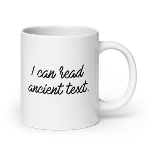 May include: White ceramic mug with black text that reads "I can read ancient text."
