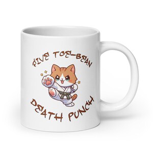May include: White ceramic mug with a cartoon illustration of a cat in a karate uniform. The text "Five Toe-Bean Death Punch" is printed around the cat.