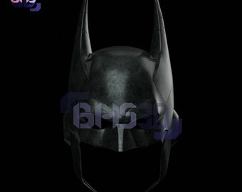 May include: A black Batman helmet with a textured surface and a pointed design. The helmet has a dark, metallic finish.