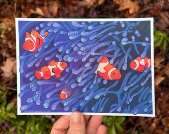 Op de afbeelding: Een kleurrijke illustratie van vijf oranje en witte clownvissen die zwemmen in een blauw en paars koraalrif. De vissen worden omringd door lange, dunne, blauwe en paarse koraaltakken.