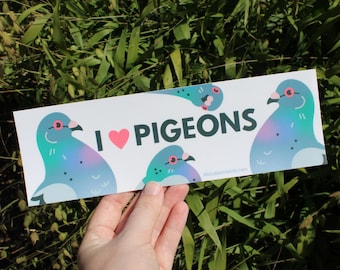 May include: A white rectangular sticker with the text "I ❤️ PIGEONS" and illustrations of blue and teal pigeons. The sticker has a pink heart and the website address "MicrobiomeArts.com".