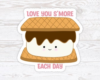 May include: A cute cartoon s'more with a smiling face and the text "Love you s'more each day" in pink letters.