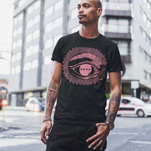 May include: A black t-shirt featuring a pink eye graphic with the text "NMAD" inside the eye. The eye is surrounded by a pink sunburst.