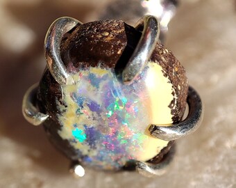 May include: A silver pendant with a brown and white opal gemstone set in a claw setting.