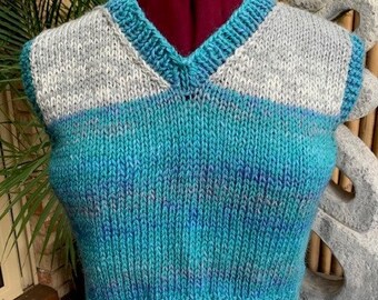 Hand knitted vest. We hand knitted this using a blue variegated acrylic yarn.  Matched with a grey highlight makes this an unique garment.