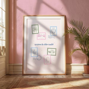 May include: A framed print with a white background and a light pink border. The print features a collection of six vintage postage stamps with illustrations of a four-leaf clover, a building, a car, a crest, a building, and a bird. The text "written by chloe walsh" is printed in blue below the stamps.