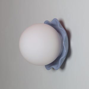 May include: A contemporary wall light with a frosted white globe shade, held by a wavy, pale blue mount. The light is fixed to a light grey wall, offering a minimalist look. The design is simple and stylish, suitable for different interior designs.