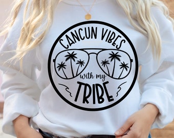 May include: White sweatshirt with a black circle graphic that says "Cancun Vibes with my Tribe" and features palm trees reflected in sunglasses.