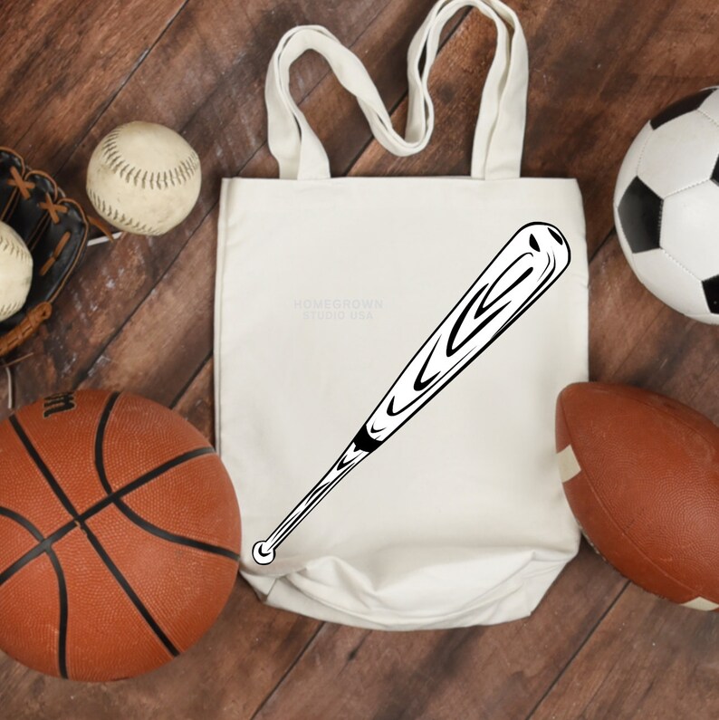 May include: A white tote bag with a black and white baseball bat graphic. The bag has the text "HOMECROWN STUDIO USA" printed on it. The bag is surrounded by sports equipment, including a basketball, baseball, football, and a baseball glove.