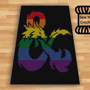 以下が含まれることがあります： 黒色の編み物で、虹色のカラフルなドラゴンのデザインが特徴です。 ドラゴンは黒い背景に配置されています。 「Sew You Crochet」の文字が右上隅にあります。