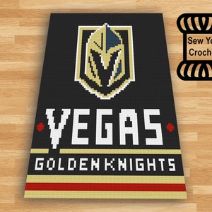 Op de afbeelding: Een zwart en gouden haakpatroon met het logo van de Vegas Golden Knights, de woorden "VEGAS" en "GOLDEN KNIGHTS", en een rode ster aan elke kant van het woord "VEGAS".