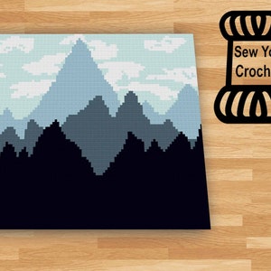 Peut inclure: Un modèle de crochet représentant un paysage de montagne bleu et blanc avec une silhouette noire d'arbres à la base. Le modèle est intitulé "Sew You Crochet".