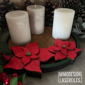 Può includere: Una ghirlanda dell'Avvento in legno con tre candele bianche e due decorazioni di stella di Natale rosse. La ghirlanda ha un anello esterno verde e un centro in legno marrone.