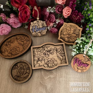 May include: A set of five laser cut wooden trays and ornaments featuring a floral design. The trays are in various sizes and shapes, with a dark brown stain. The ornaments are round and feature the words "Home" and "Mom" in purple.