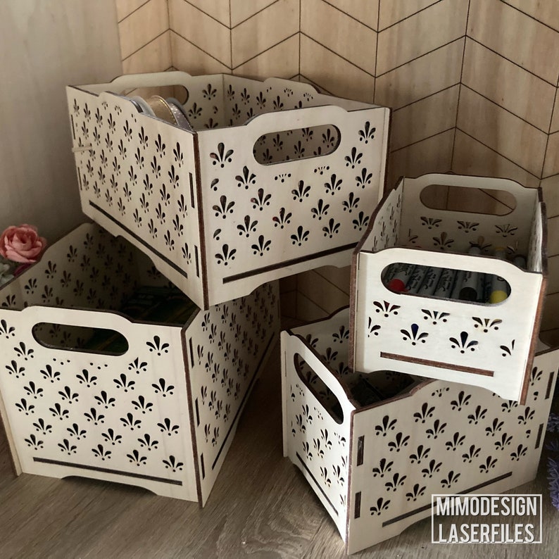 May include: Four wooden storage boxes with a decorative floral pattern and cutout handles. The boxes are stacked on top of each other. The boxes are made of light wood with a natural finish.