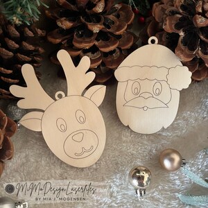 May include: Two unfinished wooden Christmas ornaments, one of Santa Claus and one of a reindeer. Both ornaments have black outlines of facial features.